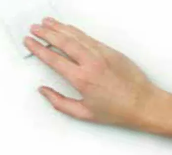 Een hand veegt de achterkant van de muurcirkel schoon op de plek waar de plaat komt